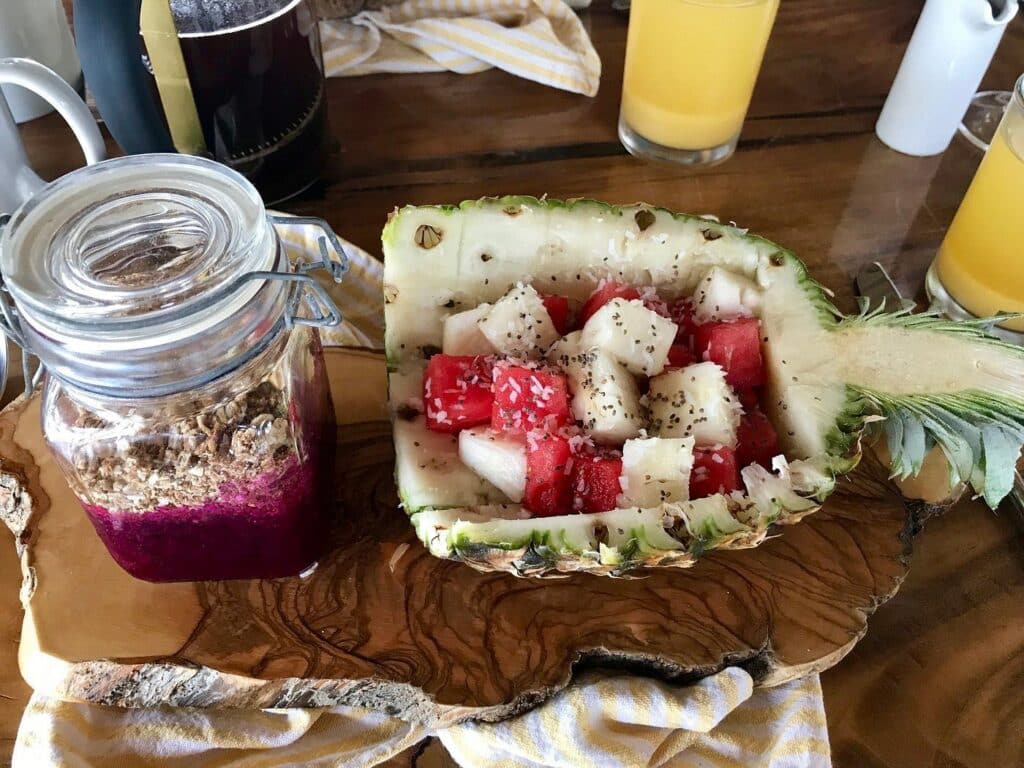 Acai bowl in a jar and cut up fruit in a pineapple shell - a breakfast setup