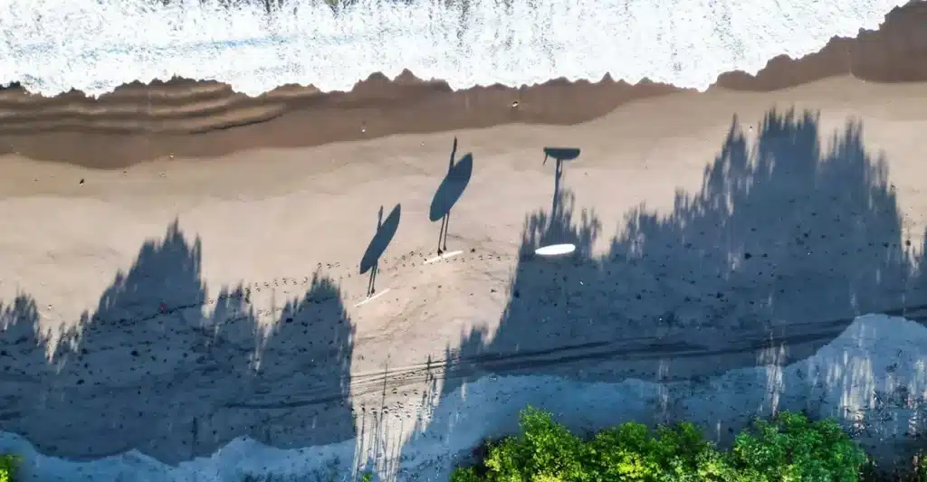 Three surfers carrying their boards to the surf in Nicaragua